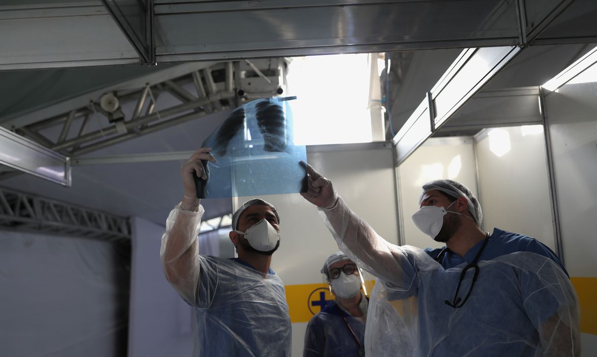 Médicos observam exame de paciente em hospital